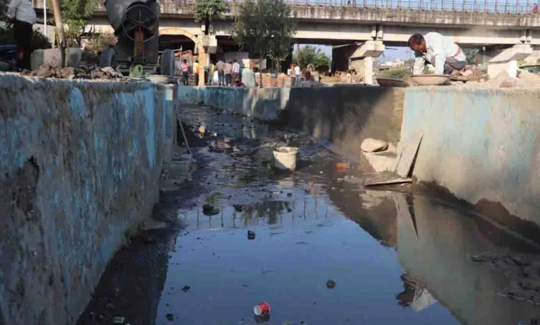 People clean a riverside channel for Chhath Pooja